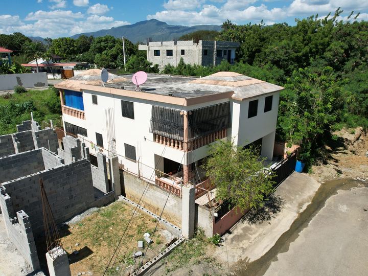 Vivienda de dos niveles a medio terminar junto a una construcción vecina
