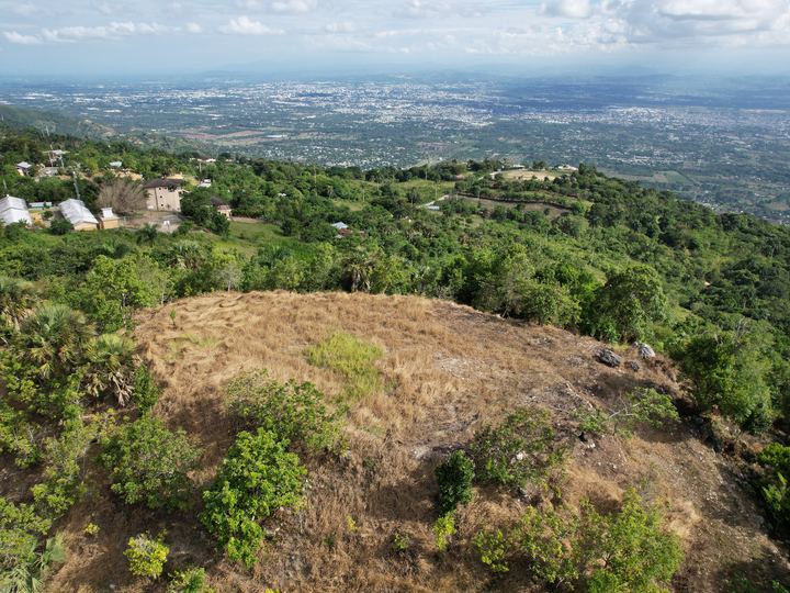 Terreno desmontado en la ladera de una loma con la ciudad al fondo