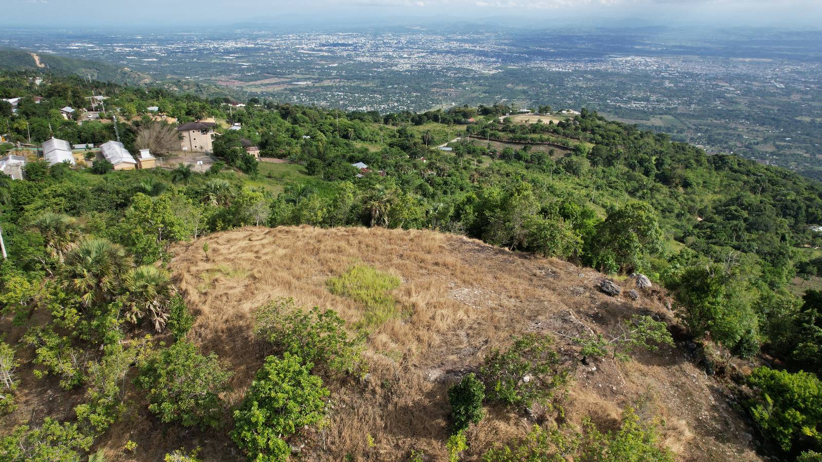 Terreno en la ladera de una loma con la ciudad al fondo, visto desde el aire